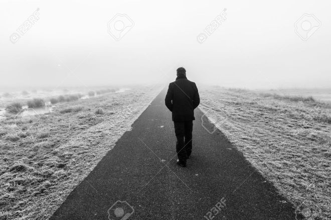 35957453-man-walking-away-on-an-empty-desolate-raod-stock-photo
